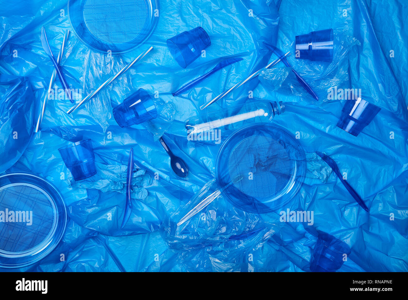 top view of blue crumpled polyethylene bag with plastic bottles, cups, plates, knives, spoon ang sponge Stock Photo