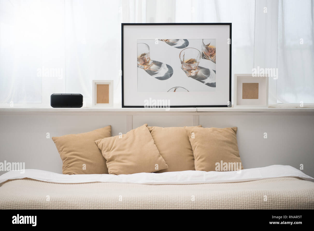 bedroom with brown pillows on bed, alarm clock, picture and photo frames Stock Photo