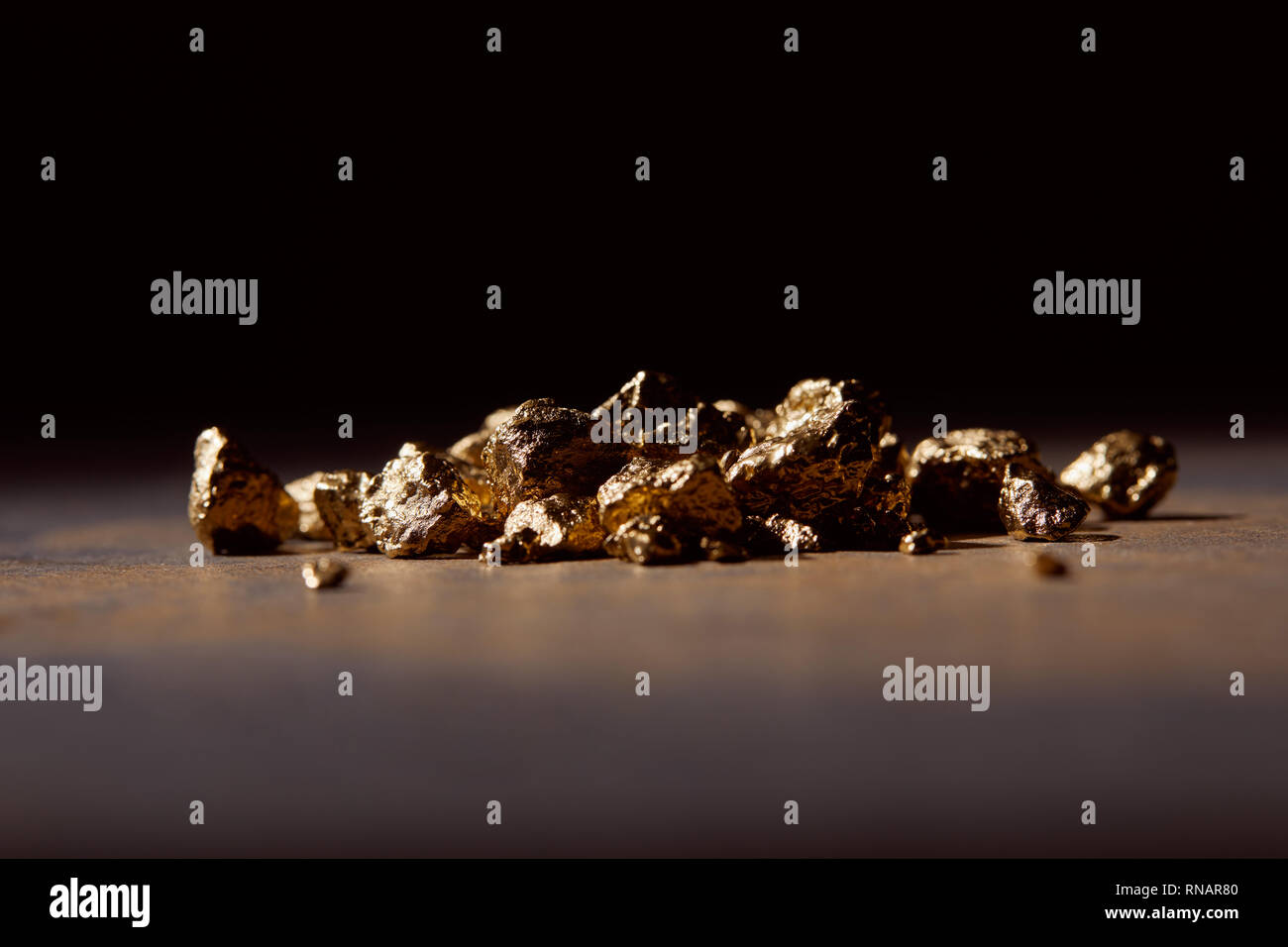 unwrought golden stones at dark on marble table and black background Stock Photo