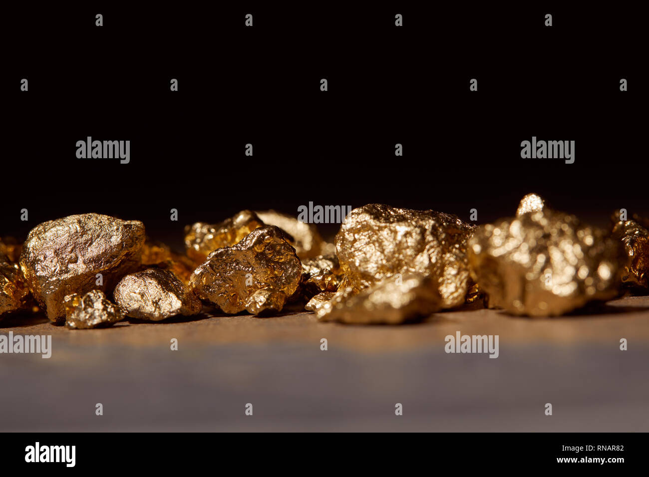 golden stones on marble table isolated on black Stock Photo