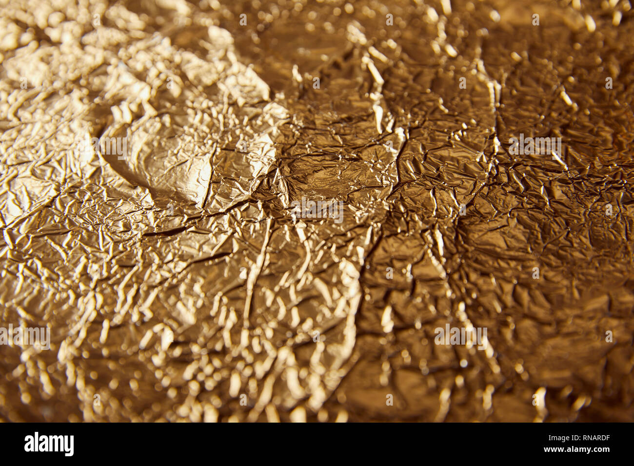 sheet golden foil with blurred bright glares Stock Photo