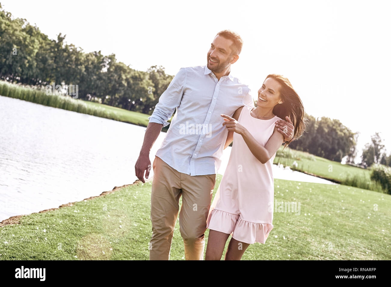 Romantic time young couple walking in the park looking at lake aside