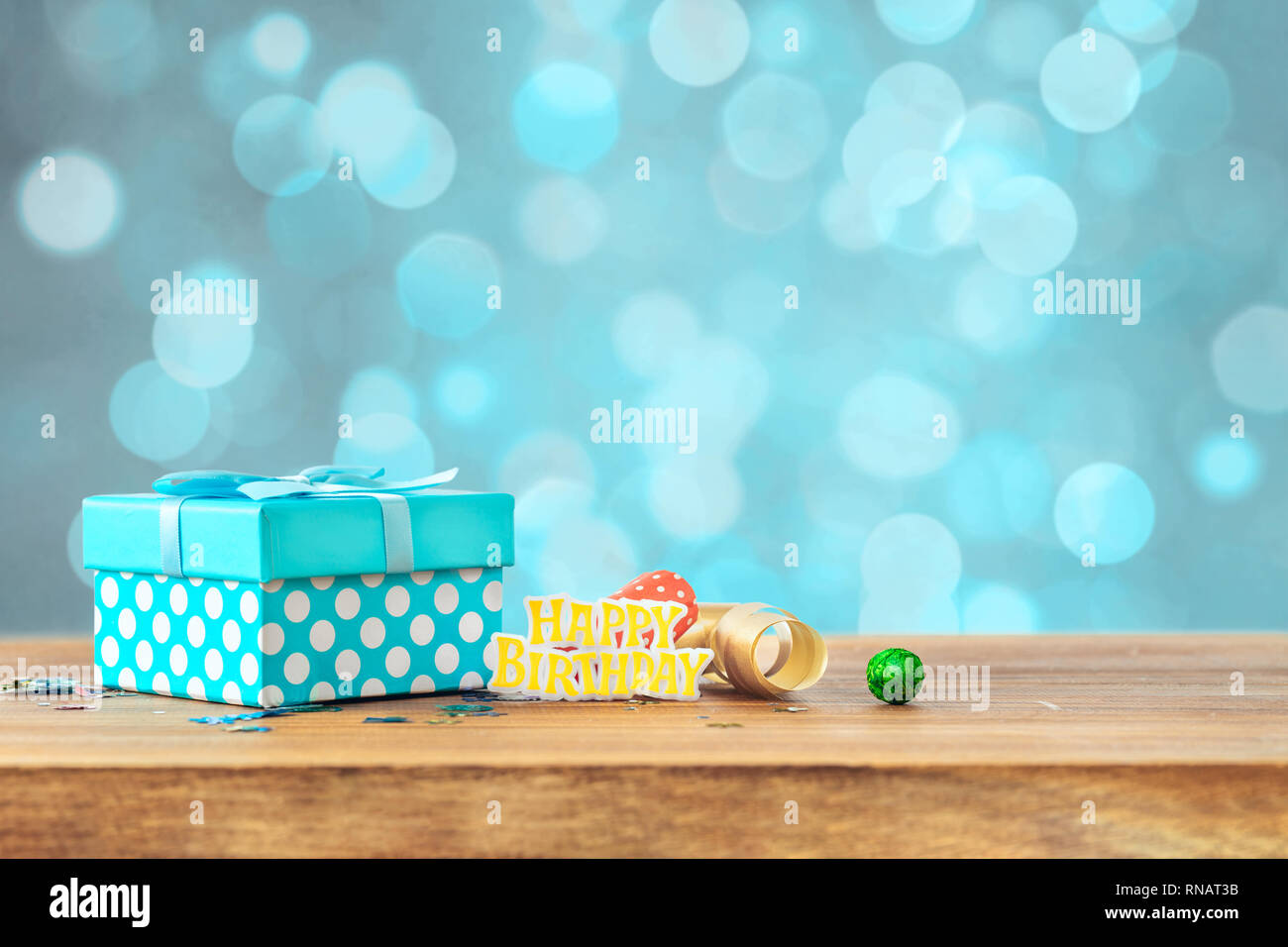 Blue gift box on wooden table with the word birthday against bokeh