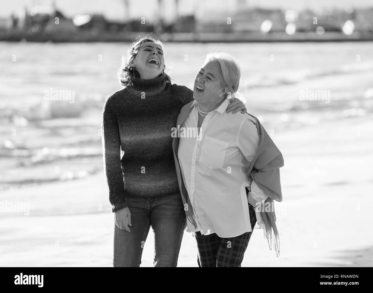 Portrait of happy senior mother and adult daughter spending time together holding hands laughing and walking on beach at sunset light in Happy family  Stock Photo