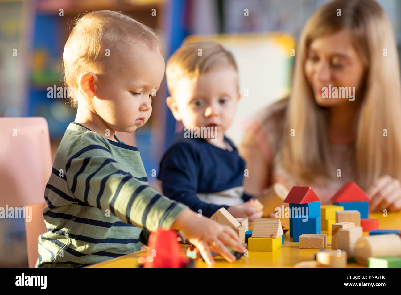 Nursery babies kids playing with teacher in kindergarten Stock Photo