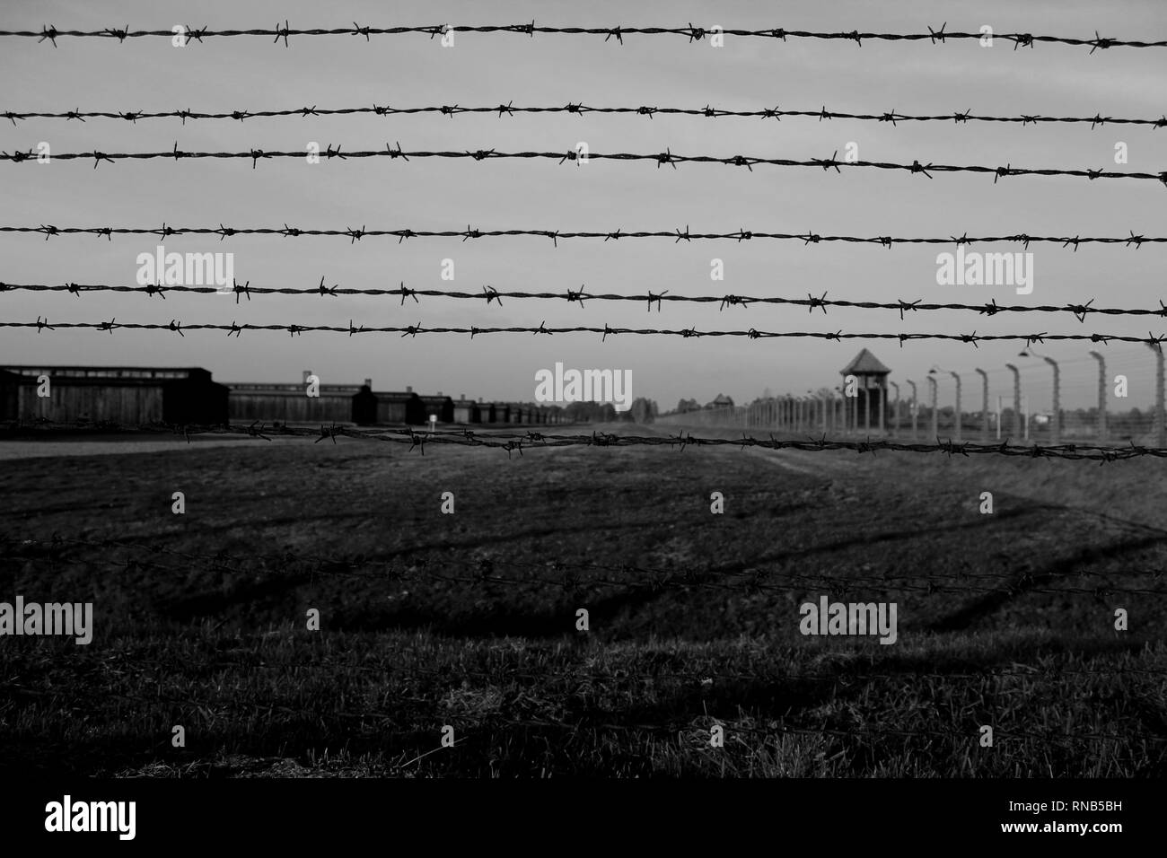 Buildings at Auschwitz through barbed wire Stock Photo