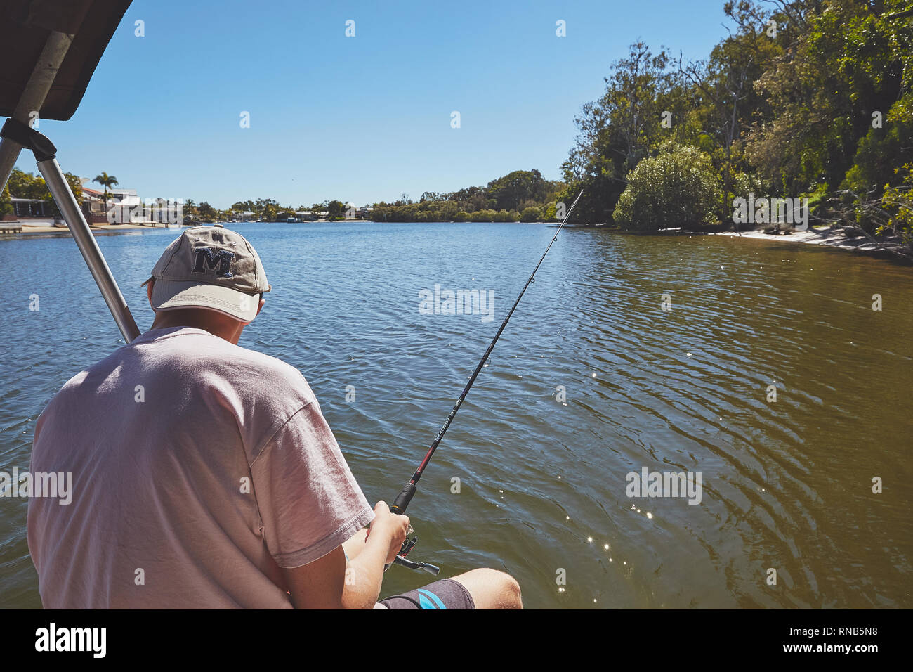 Teenage male on a small boat, fishing, on a river in Queensland, Australia Stock Photo