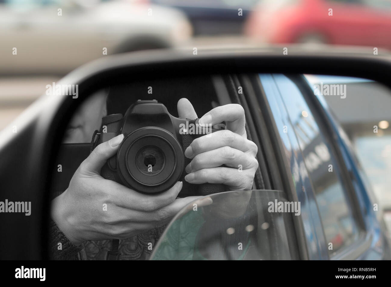 Reflection in side view mirror of someone with DSLR camera. Hidden photographing, paparazzi concept Stock Photo