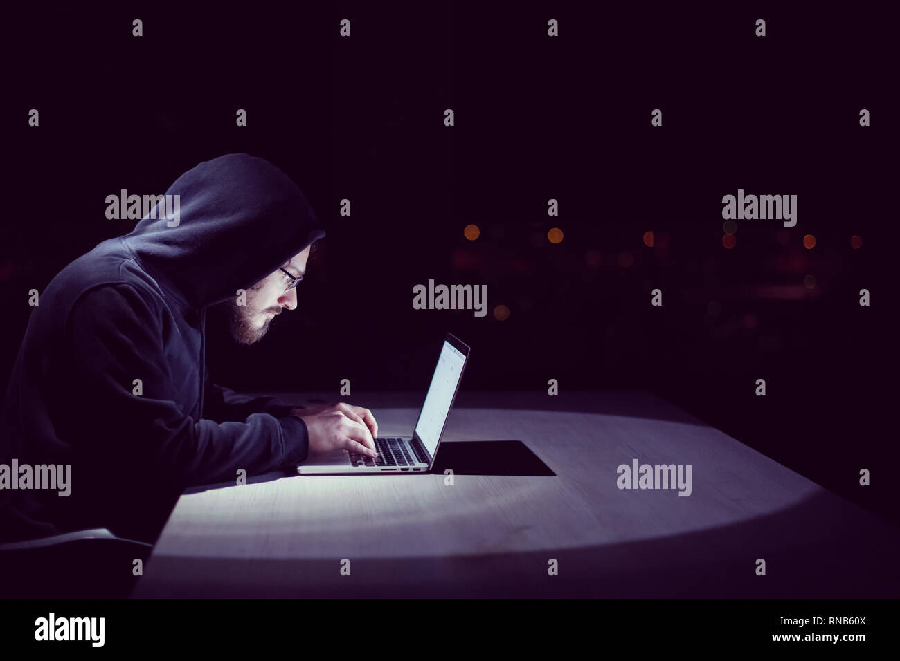 Young talented hacker using laptop computer while working in dark ...