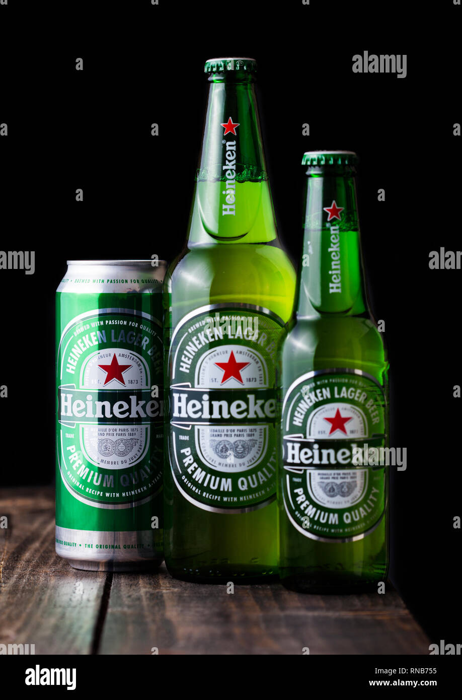 LONDON, UK - FEBRUARY 06, 2019: Bottles and aluminium can of Heineken Lager Beer on dark wooden background. Heineken is the flagship product of Heinek Stock Photo