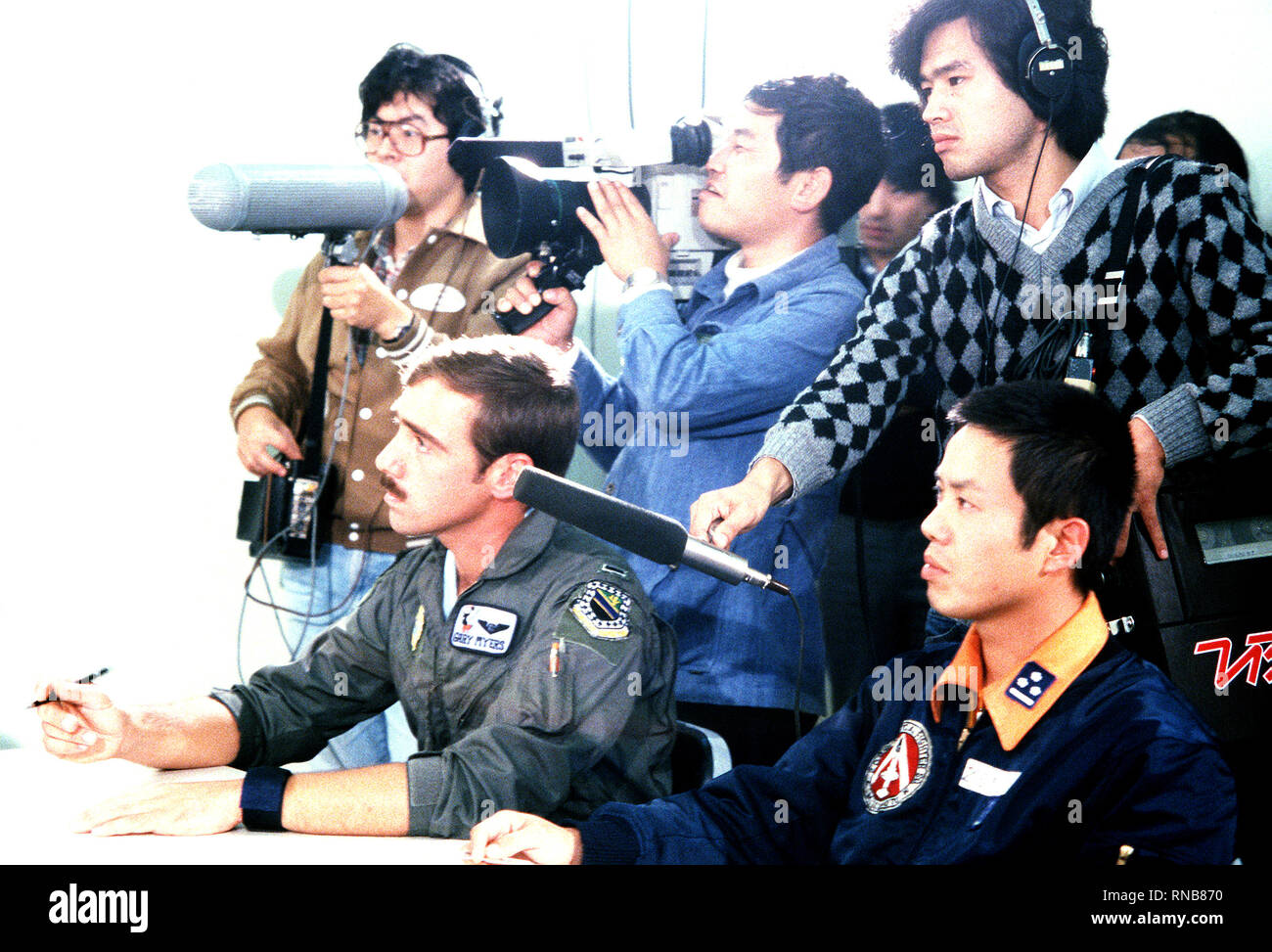 A Japanese national television crew documents the briefing of U.S. Air Force and Japanese Air Self Defense Force pilots during exercise Cope North '80.  A U.S. Air Force F-4E Phantom II aircraft pilot assigned to the 3rd Tactical Fighter Wing is to the left. Stock Photo