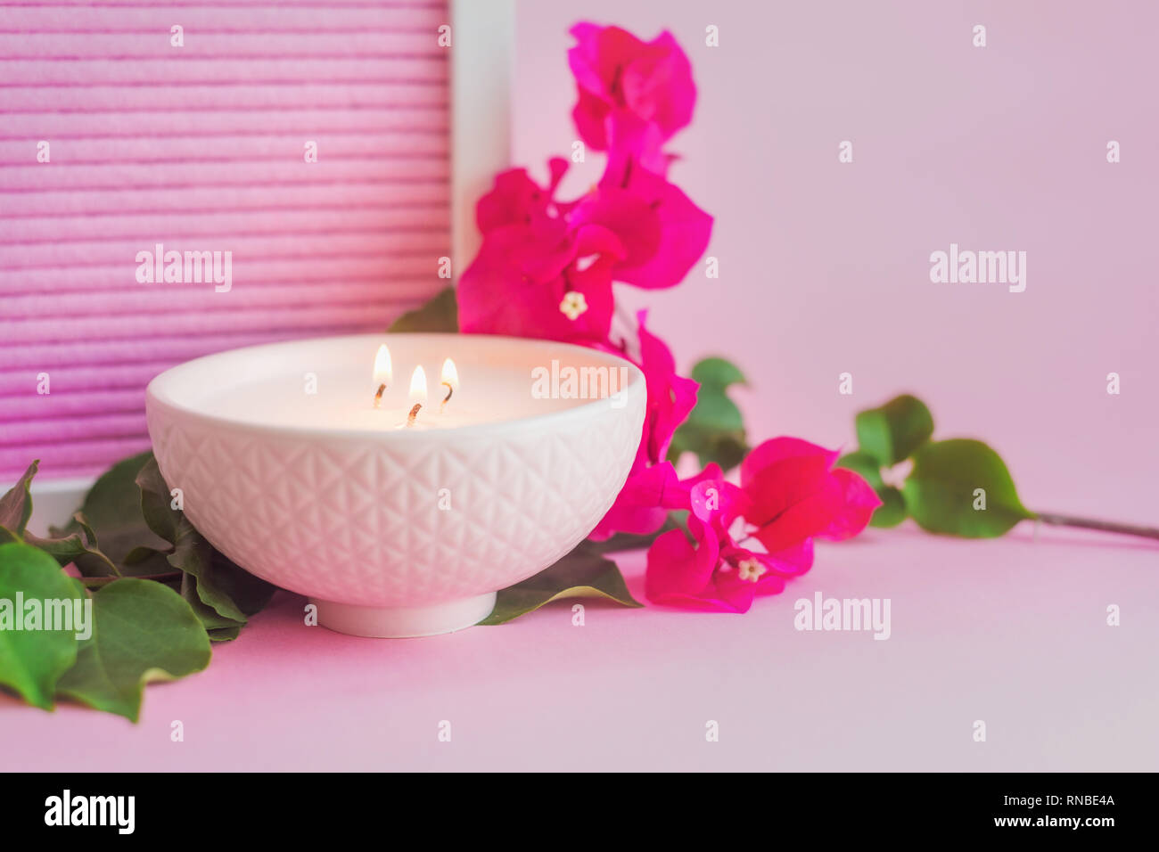 pink ceramic bowl with candle, and pink flower, on a pink background Stock Photo