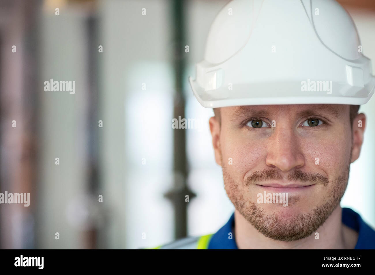 Portrait Of Male Construction Worker On Building Site Wearing Hard Hat Stock Photo