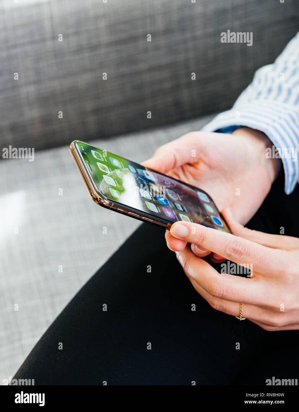 PARIS, FRANCE - SEP 27, 2018: hands using the newest latest iPhone Xs and Xs Max smartphone telephone from Apple Computers on office living room sofa Stock Photo