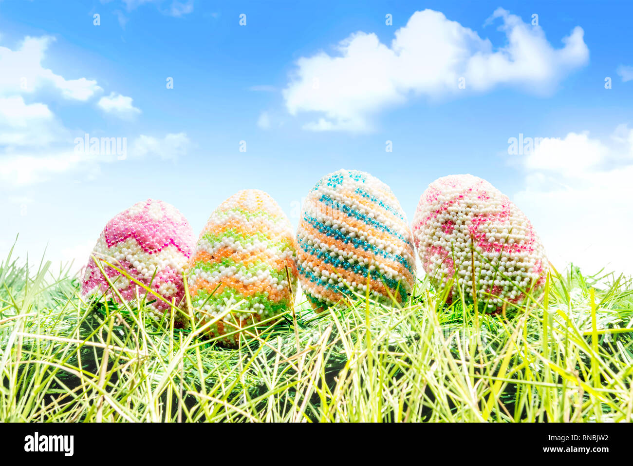 Colorful easter eggs on the green grass with blue sky background. Happy ...