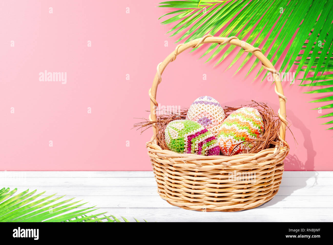 Colorful easter eggs on the nest in wooden basket on white wooden table ...