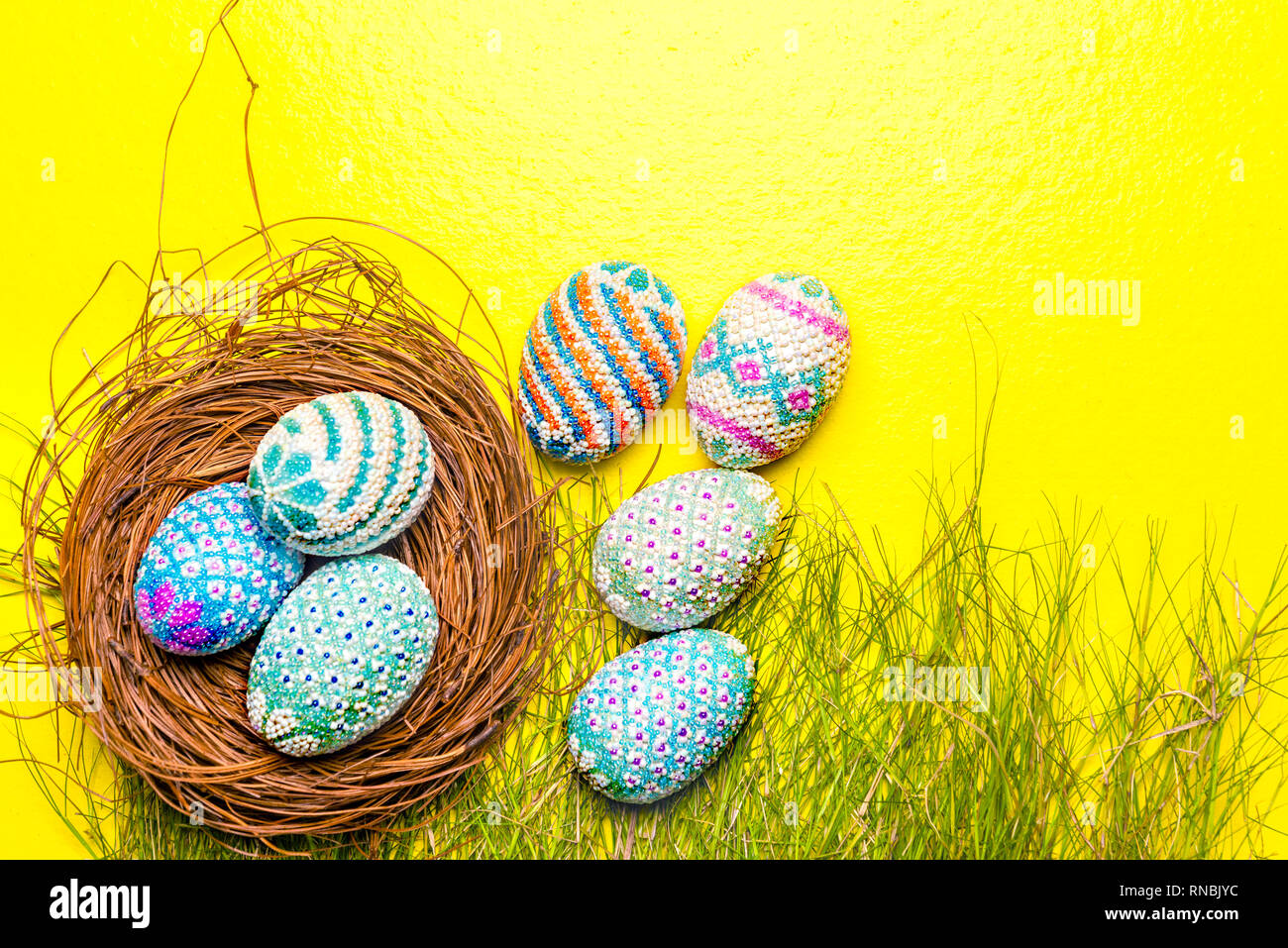 Colorful easter eggs in the nest and grass with yellow background ...