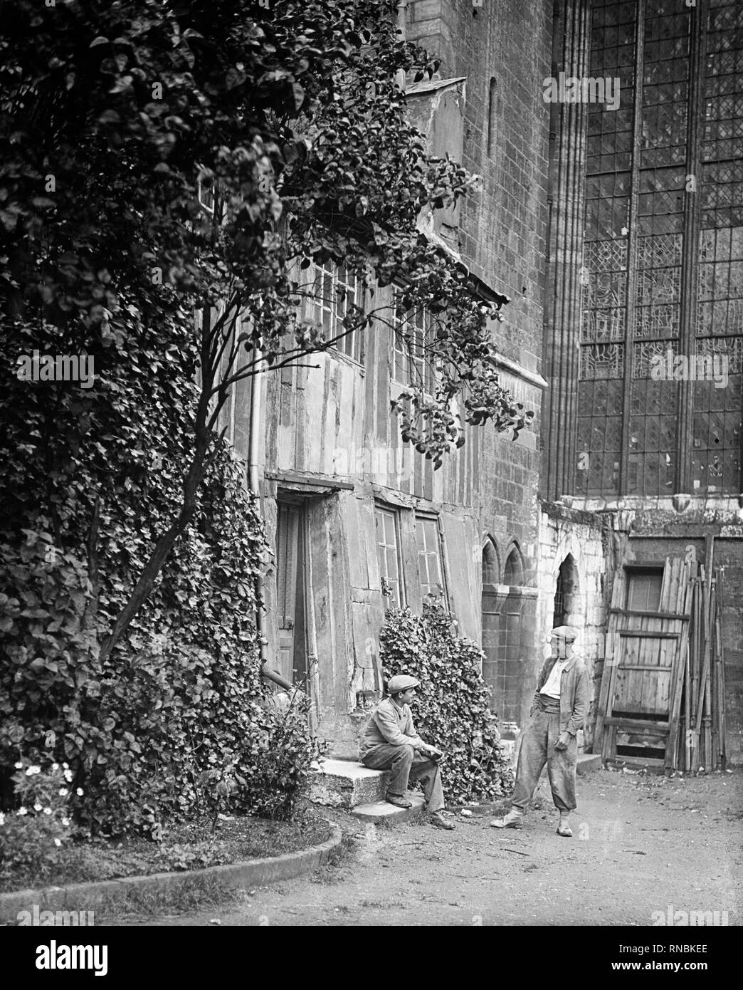 In Rouen, Normandy, two Victorian workmen take a break outside Rouen Cathedral, Notre Dame de Rouen Stock Photo