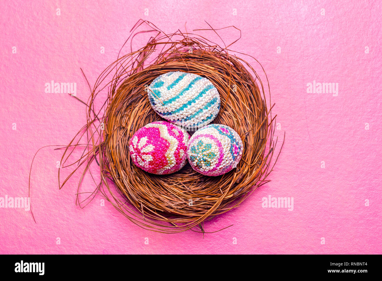 Close up view of Colorful easter eggs in the nest with pink background ...