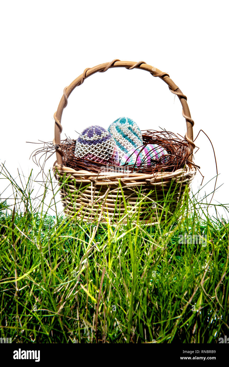 Colorful easter eggs in the nest on wooden basket at green grass over ...