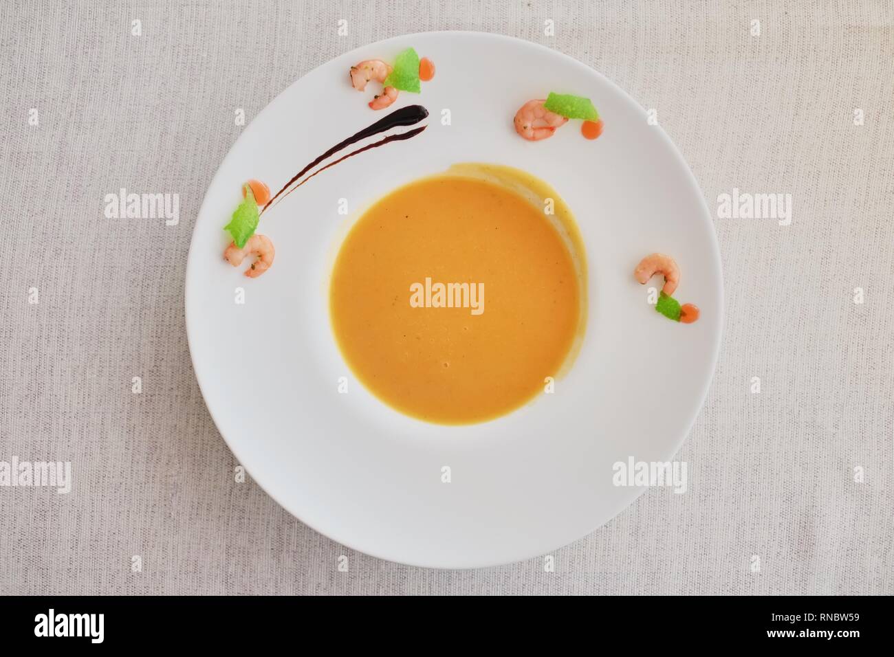Vegetable cream soup with carrot in white bowl. Top view on a rough ...