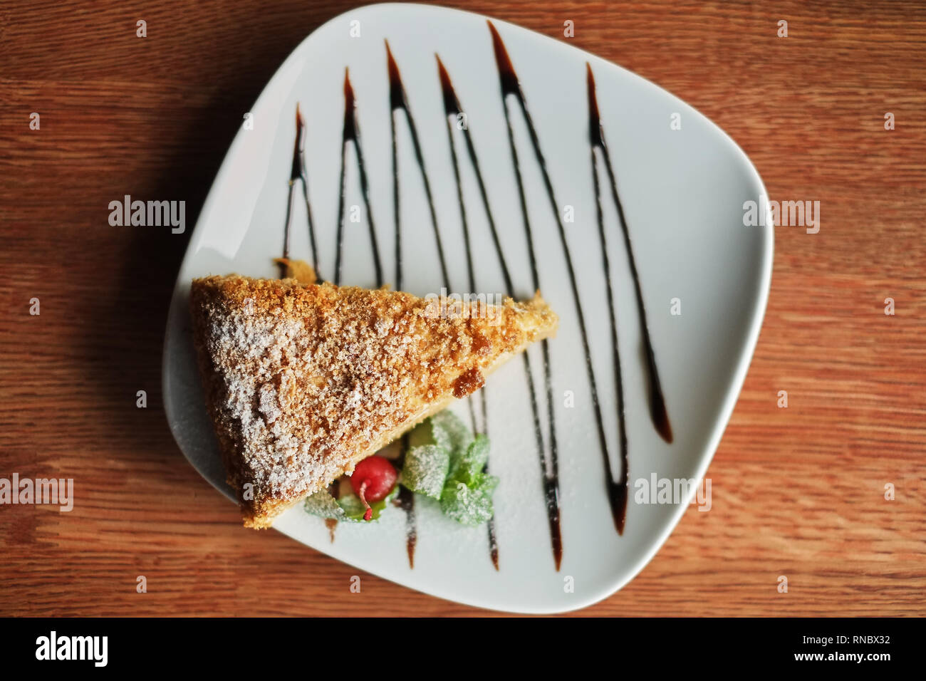 a piece of poured honey cake with chocolate topping on a plate, top view, set. Stock Photo