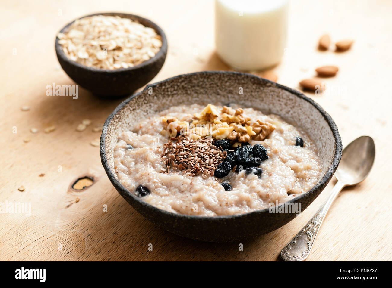 Oatmeal porridge with raisin and seeds in bowl on wooden table. Tasty healthy breakfast. Morning vegan meal Stock Photo