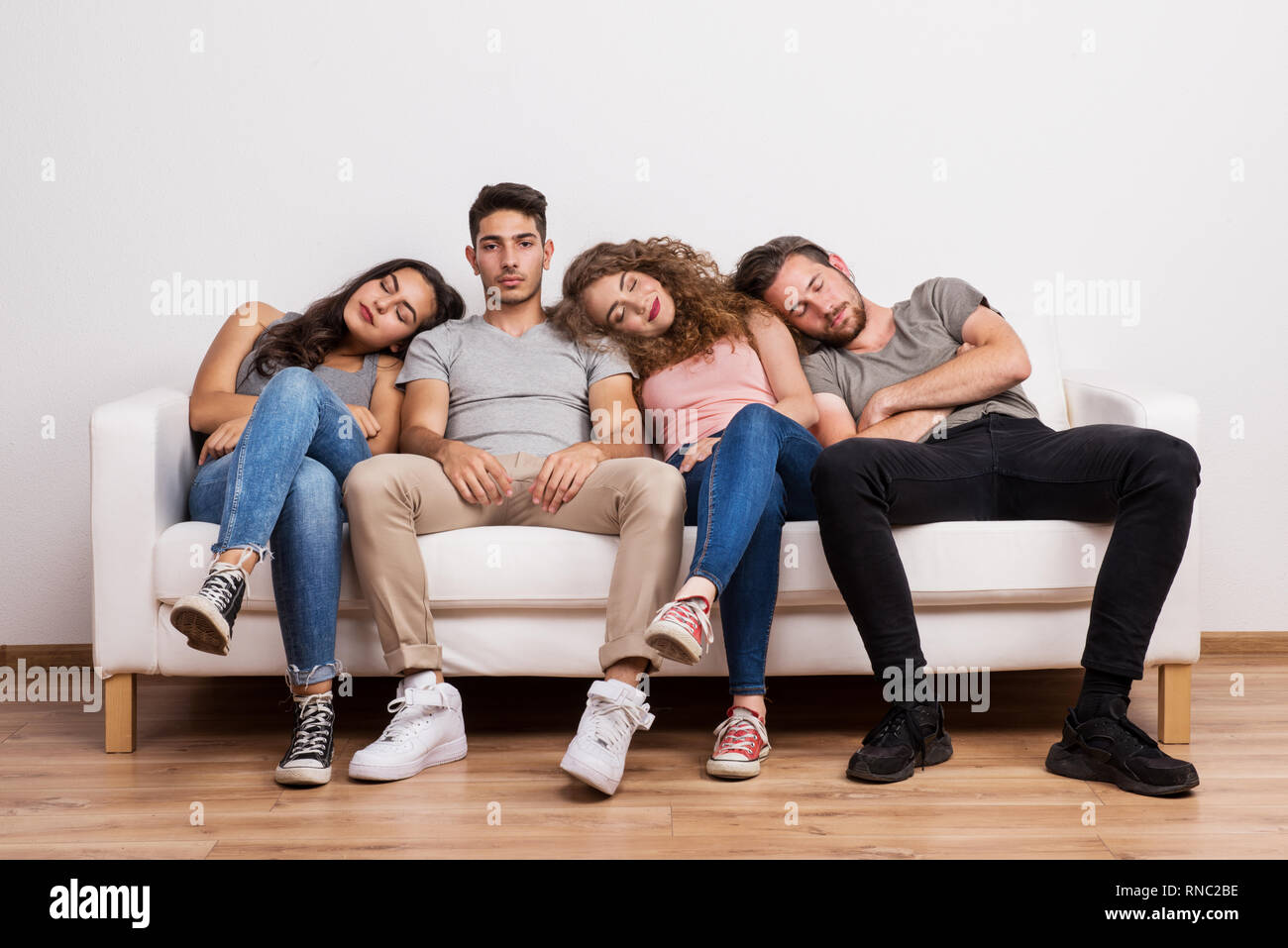 Portrait of young group of friends sitting on a sofa in a studio