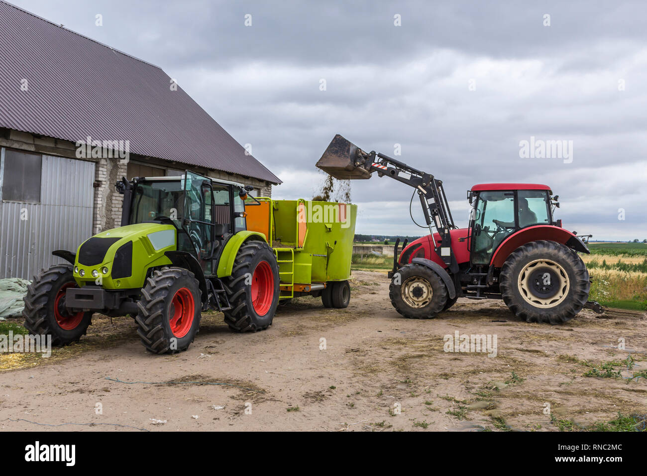 Tractor with front end loader loads the food into a distributor of animal  feed for cows. Necessary equipment for a dairy farm Stock Photo - Alamy