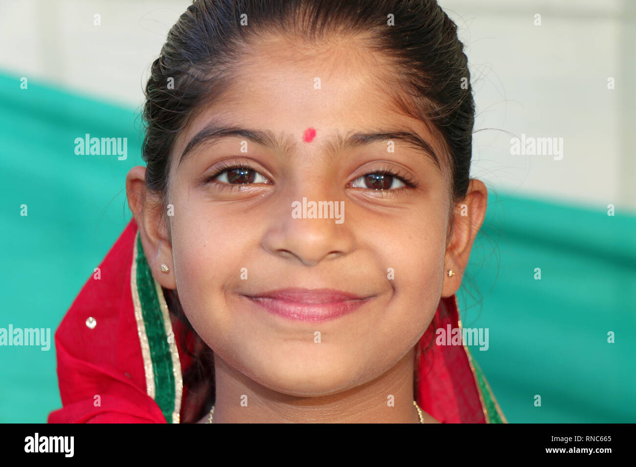 Indian cute girl with smiling face. This girl is looking very beautiful.  She is wearing red cloth and a red spot on her head Stock Photo - Alamy