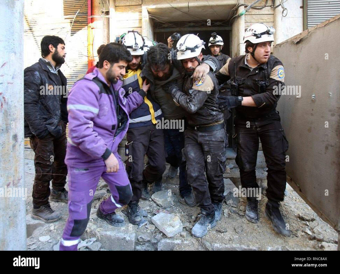 This photo released on Monday, Feb. 18, 2019 by the Syrian Civil Defense group known as the White Helmets, shows Syrian White Helmet civil defense workers carrying an injured man from a building hit by a shell from Syrian forces, in the town of Maaret al-Numan, Idlib, north Syria. Syrian government forces shelled areas held by insurgents, on Monday, in the latest violation of a September truce reached between Russia and Turkey that averted a wide government offensive on the last major rebel stronghold in Idlib province. (Syrian Civil Defense White Helmets via AP) Stock Photo