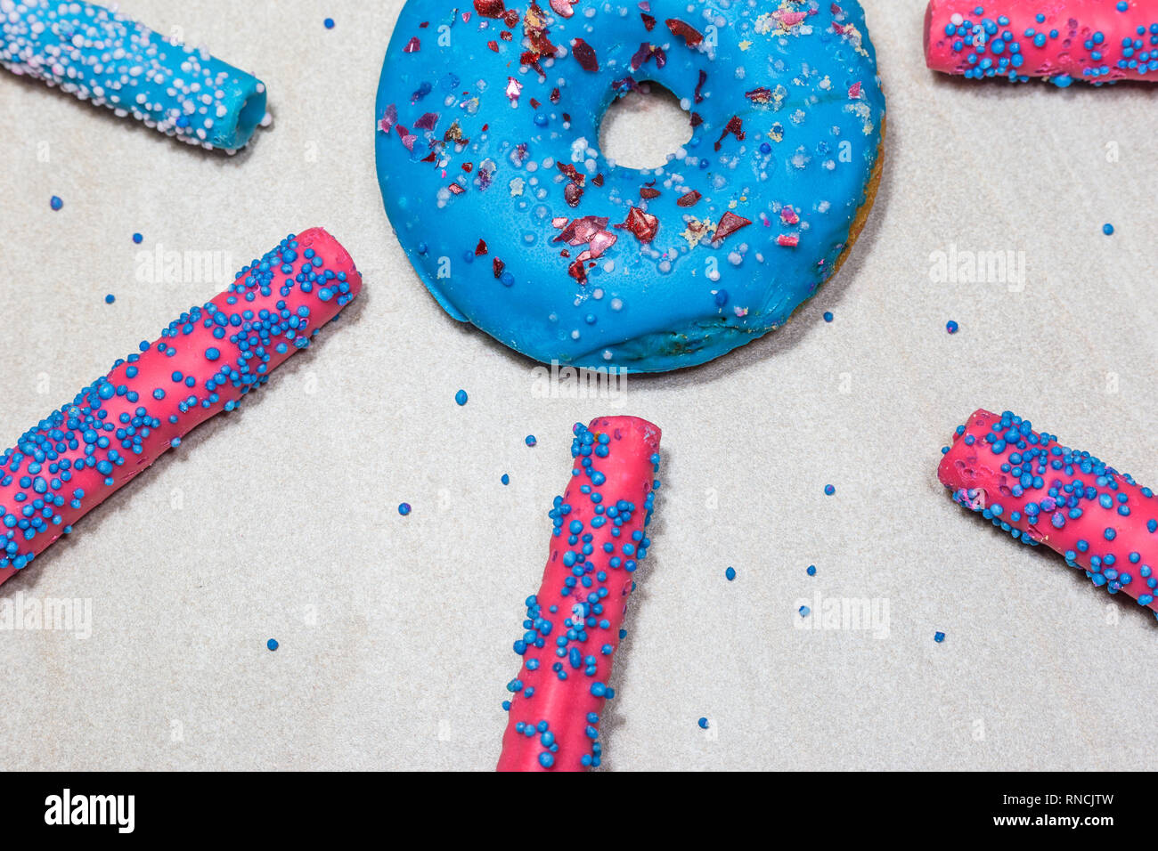 Blue glazed donuts with sprinkles and candy sticks on light background ...