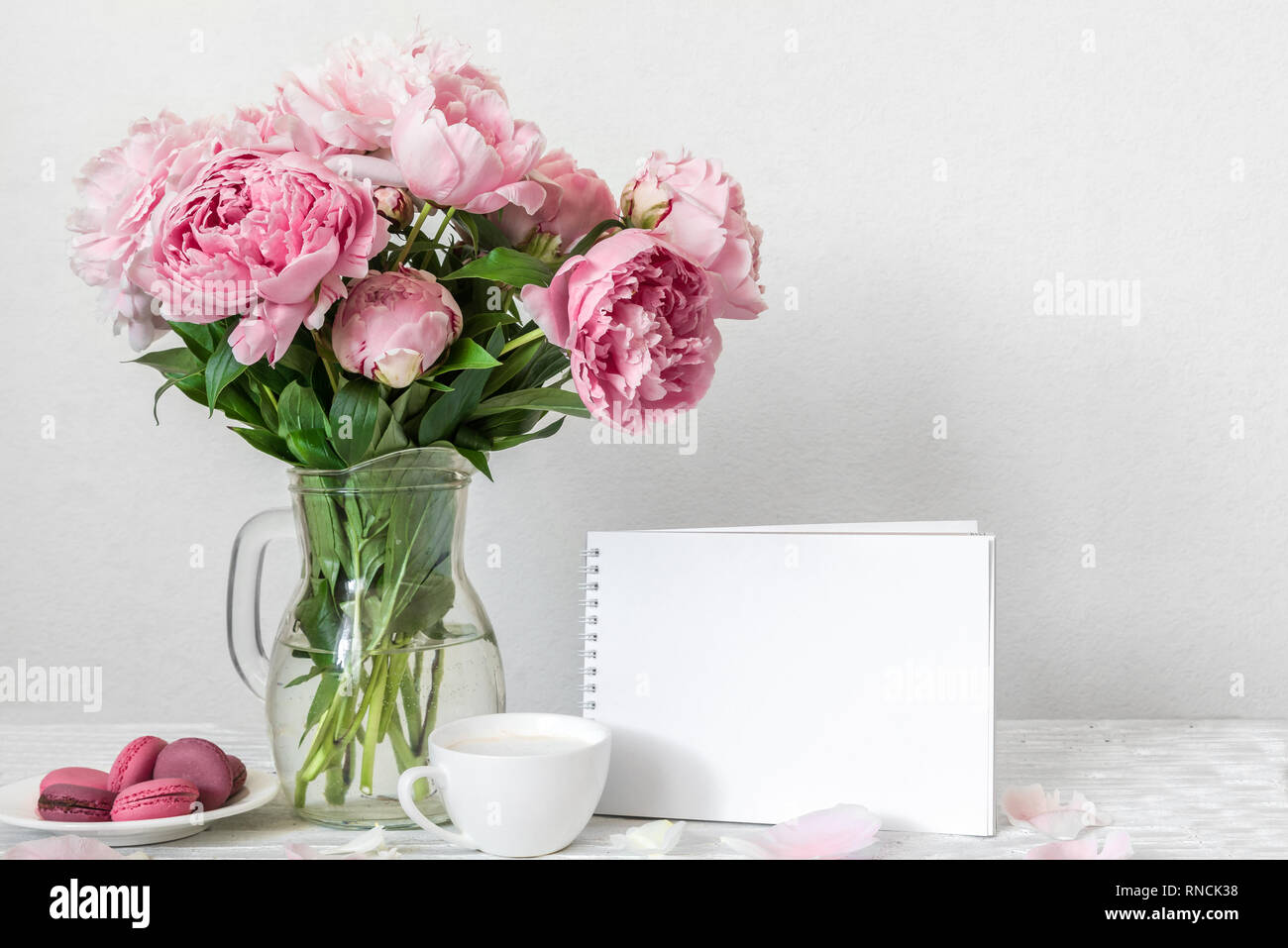 Still life with bouquet of pink peony flowers, blank greeting card, cup of  cappuccino and macaroons. mock up. holiday or wedding background. high key  Stock Photo - Alamy