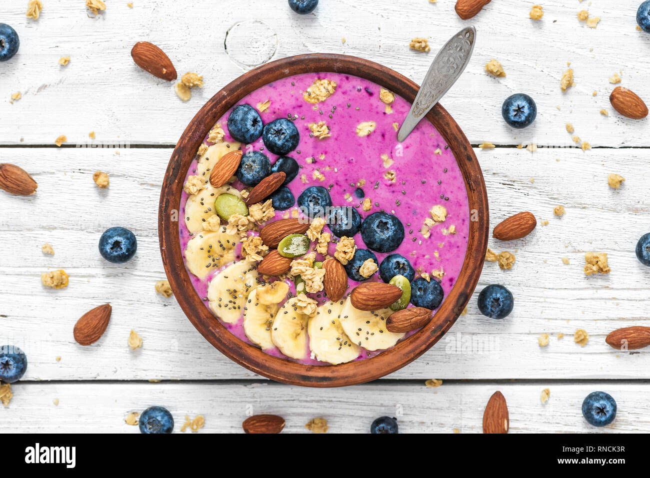 Smoothie bowl with fresh berries, fruits, nuts, seeds and granola for healthy vegetarian diet breakfast on white wooden background. top view Stock Photo