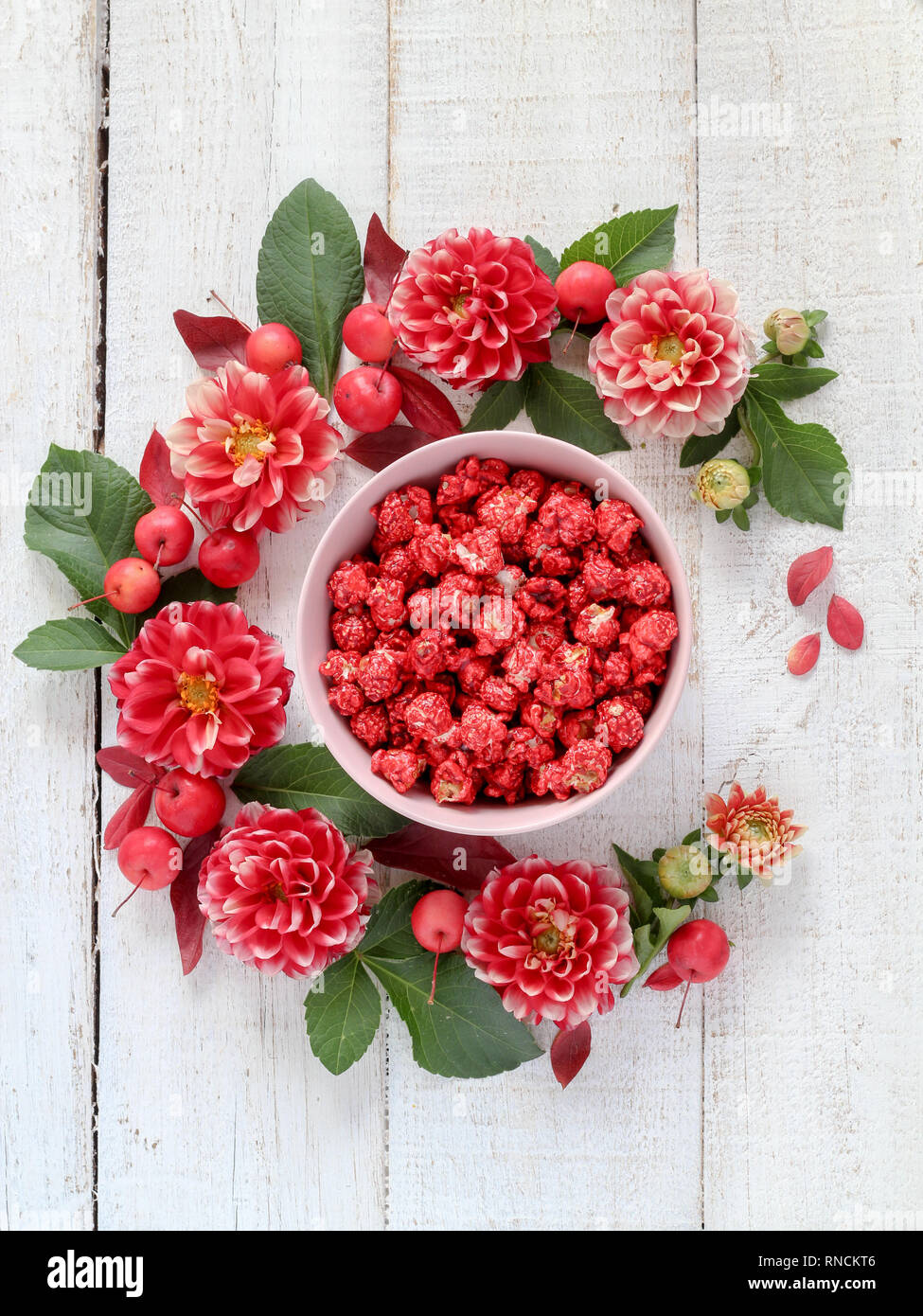Cherry flavor popcorn in bowl surrounded with red flowers Stock Photo