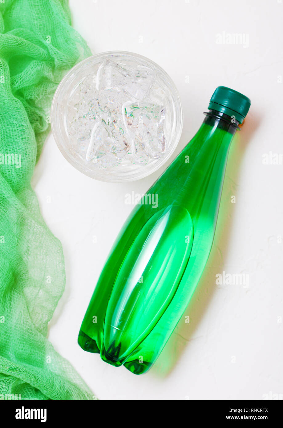 Bottle of sparkling mineral water with glass of ice and green cloth on ...