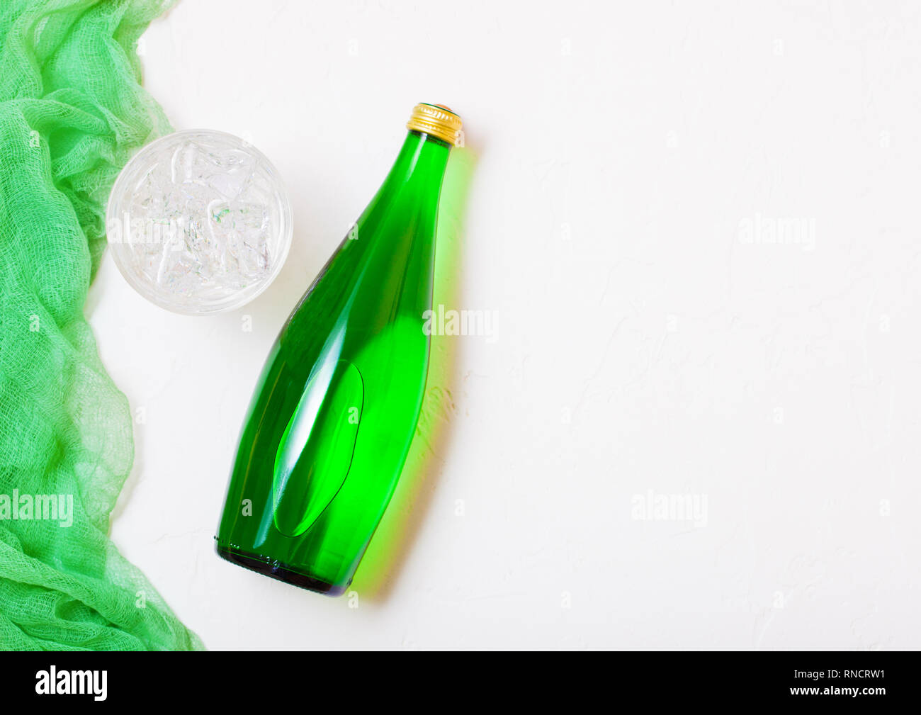 Bottle of sparkling mineral water with glass of ice and green cloth on ...