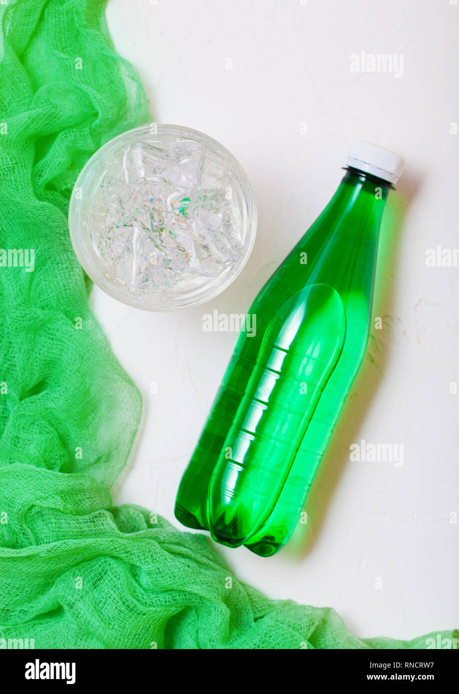 Bottle of sparkling mineral water with glass of ice and green cloth on ...
