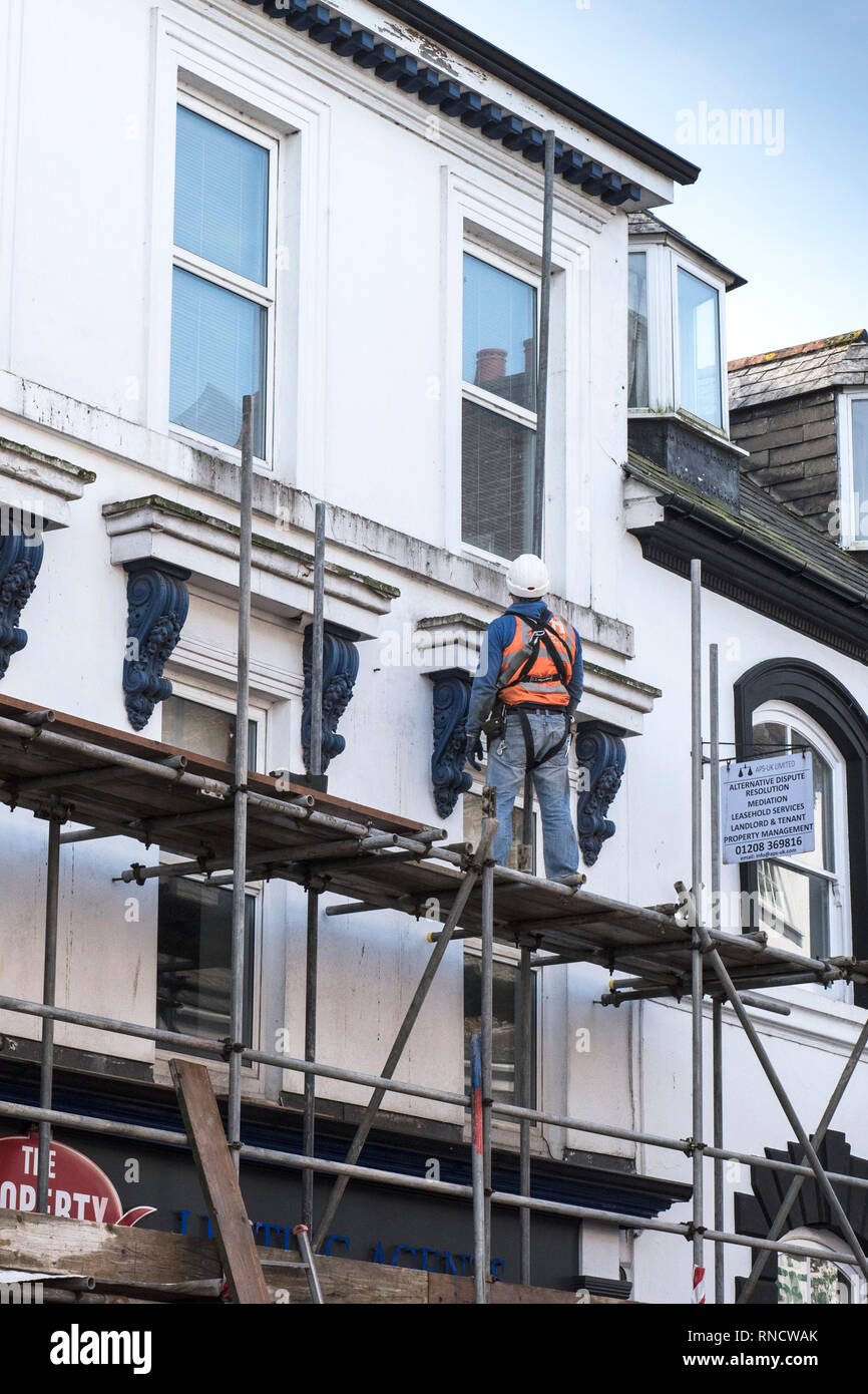 A scaffolder erecting scaffolding on the front of a building. Stock Photo
