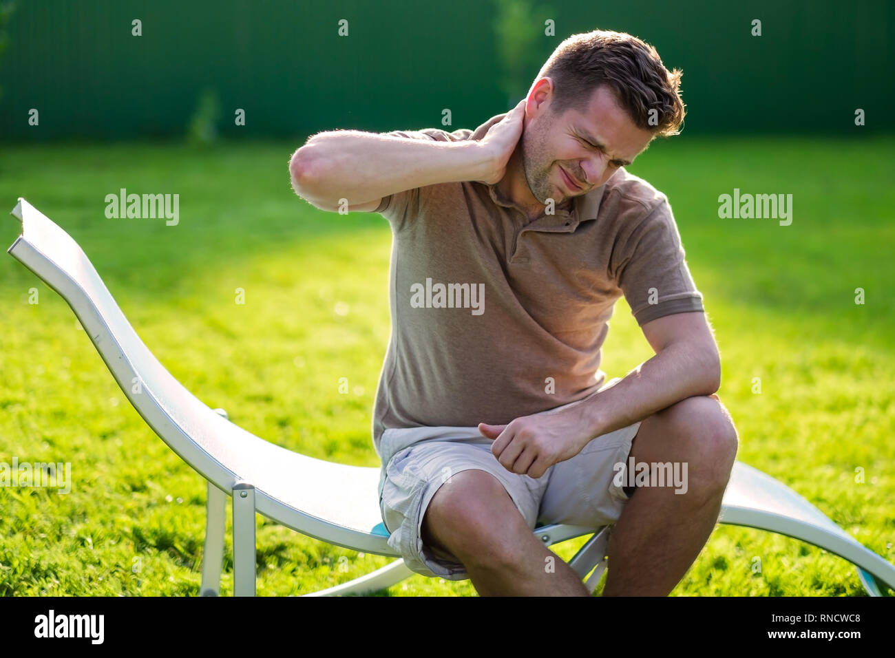 Young caucasain man having neck pain while sitting outdoor Stock Photo