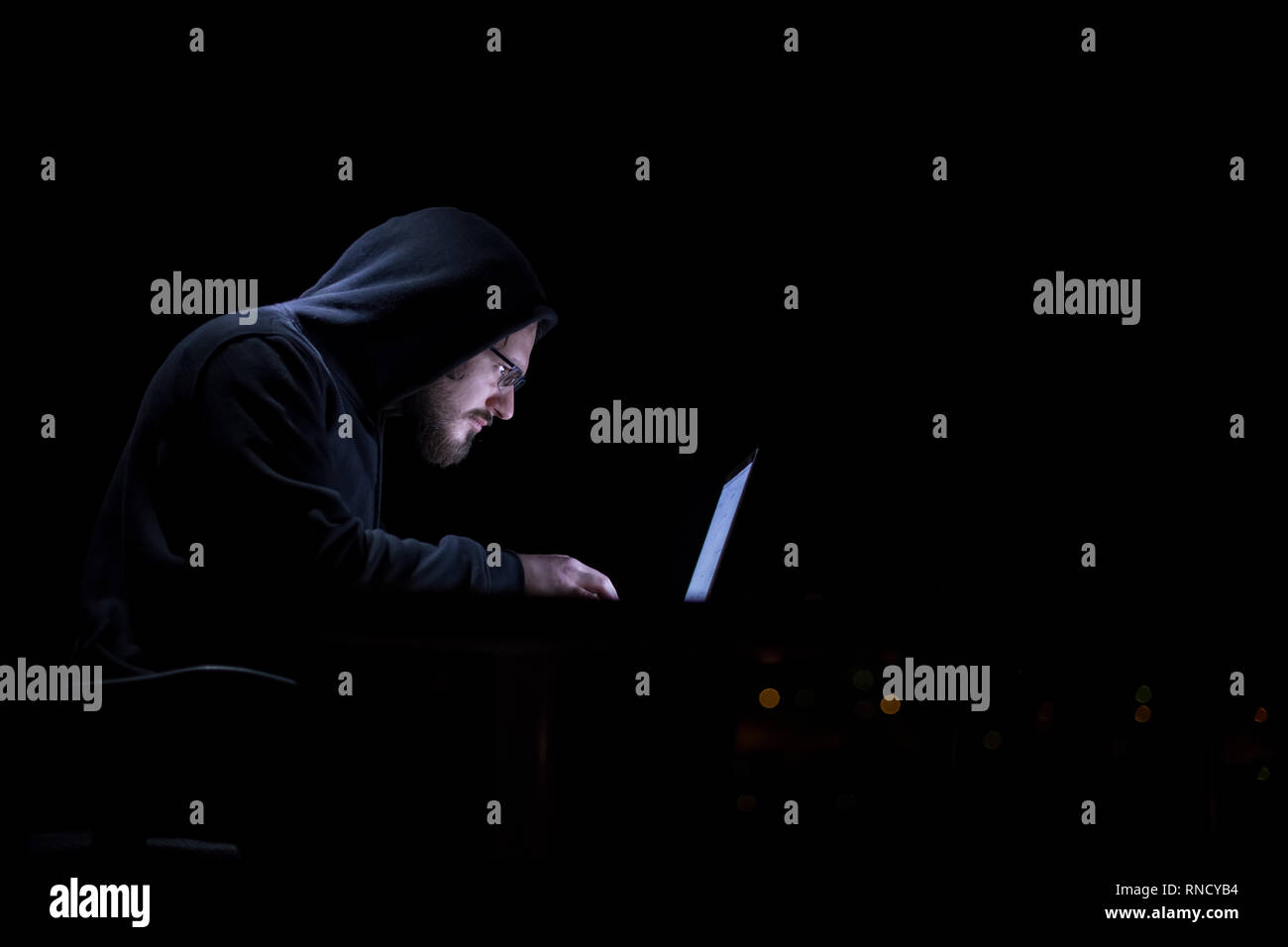 Young talented hacker using laptop computer while working in dark ...