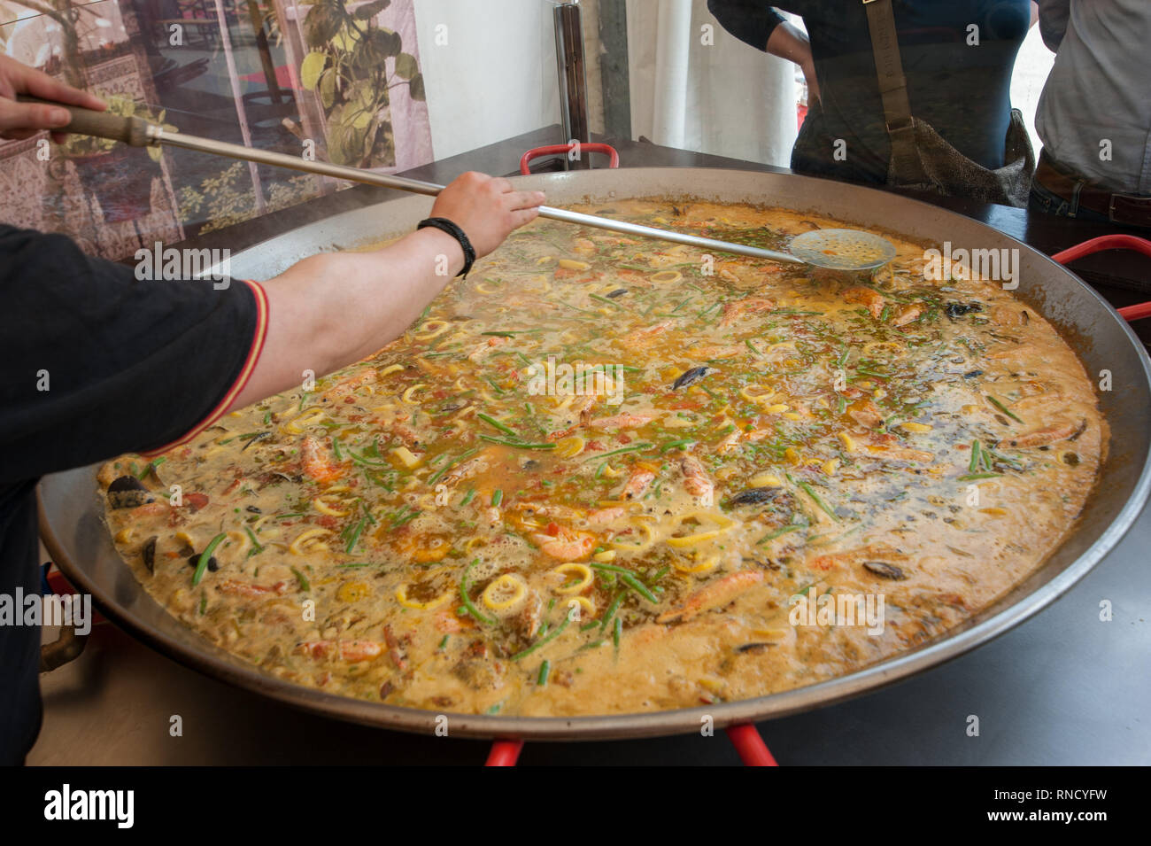 https://c8.alamy.com/comp/RNCYFW/the-cook-prepares-paella-with-seafood-mussels-shrimps-and-green-bean-in-a-extra-large-frying-pan-RNCYFW.jpg
