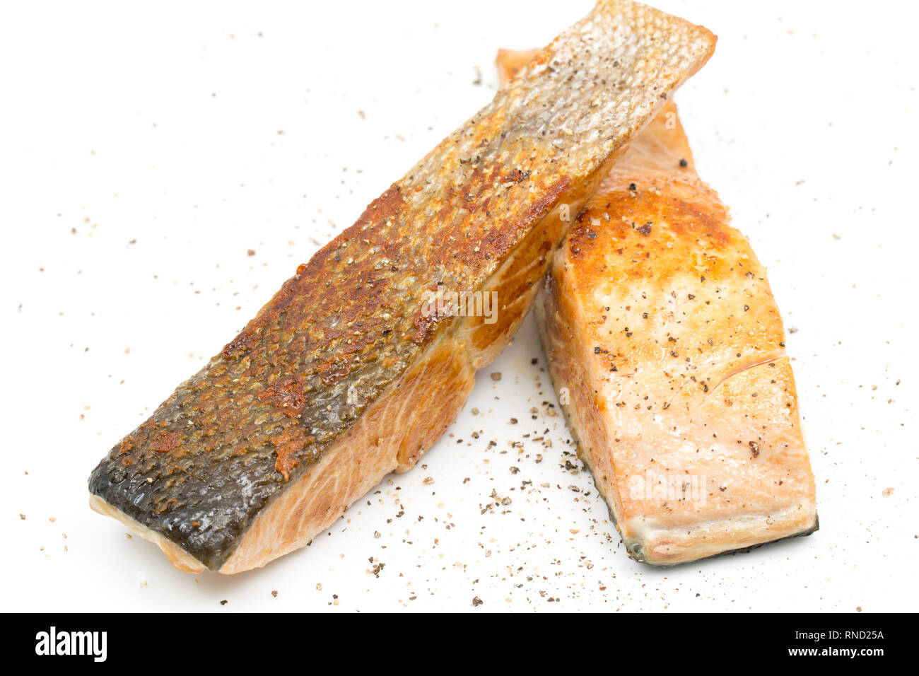 Two fried fillets of wild Keta salmon, Oncorhynchus keta, sprinkled with black pepper. Imported from the Pacific ocean and bought from a supermarket i Stock Photo