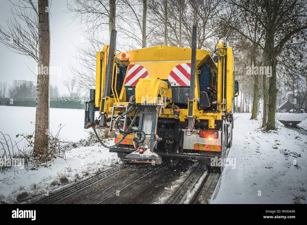 Winter service truck spreading salt and sand on the road surface to ...