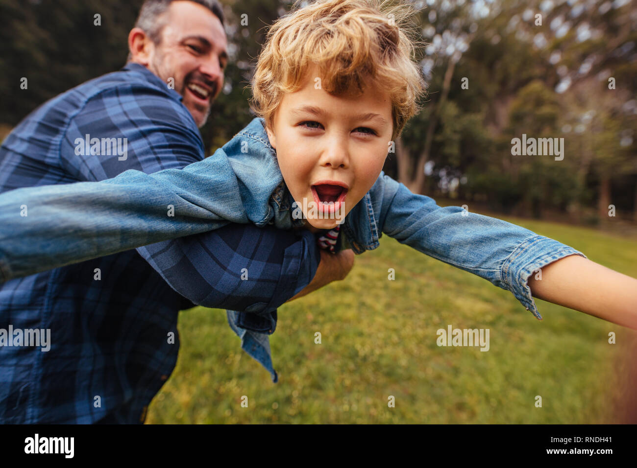 Son with his father having fun in park. Happy boy playing with dad