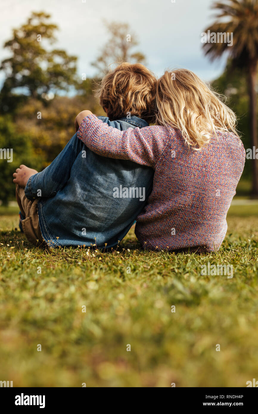 a girl and a boy holding a house cutout sitting in the grass on a