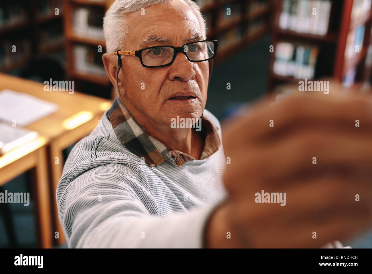 Senior lecturer teaching in class writing on the board. Portrait of a senior professor in class teaching. Stock Photo