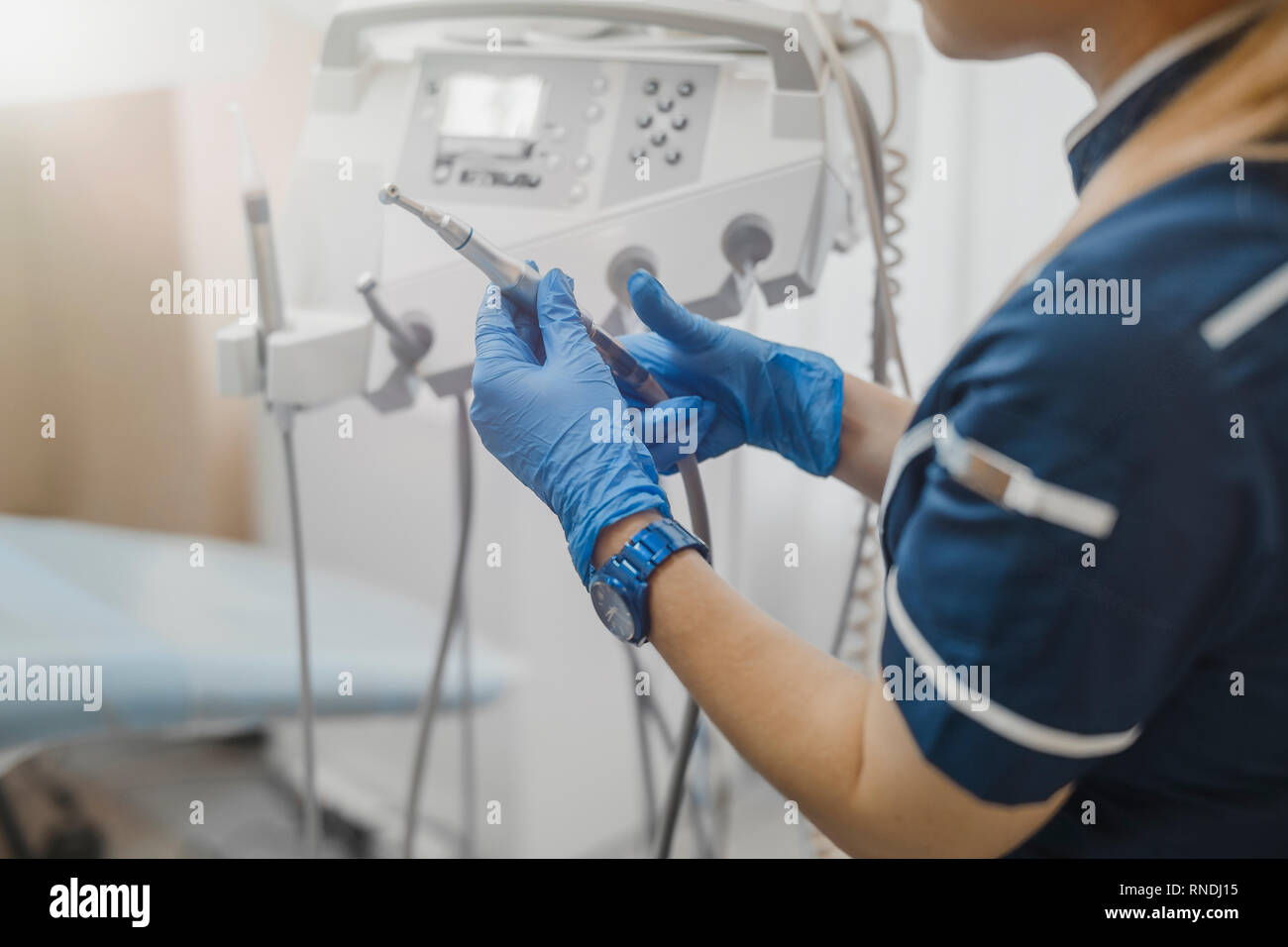 Close up of woman dentist in blue uniform checking dental equipment
