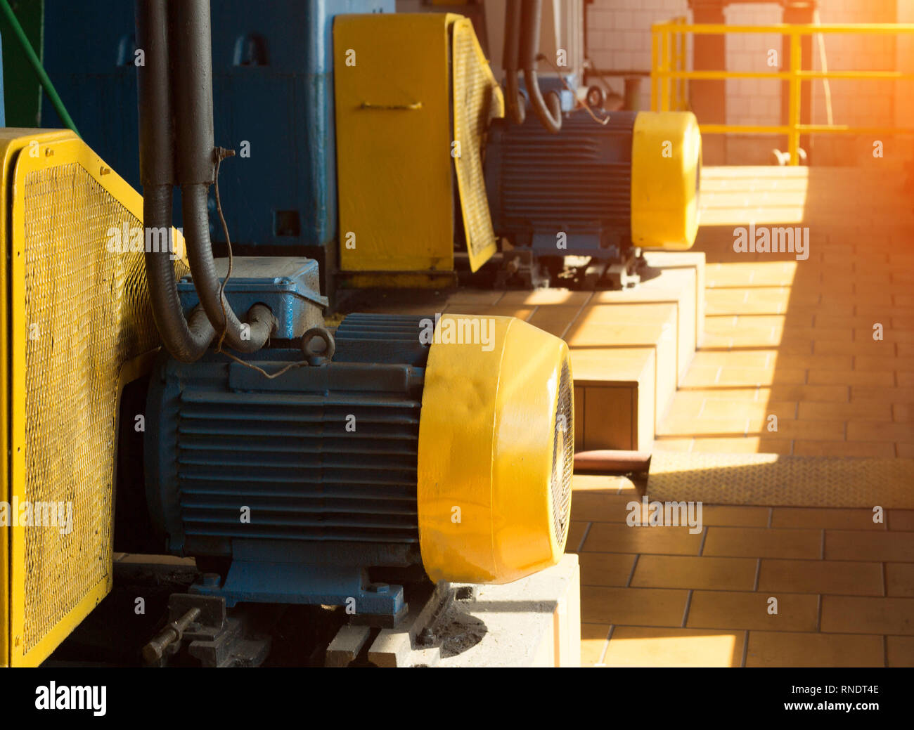 Two large electric motors in the production workshop, against the background of sunlight, industrial Stock Photo