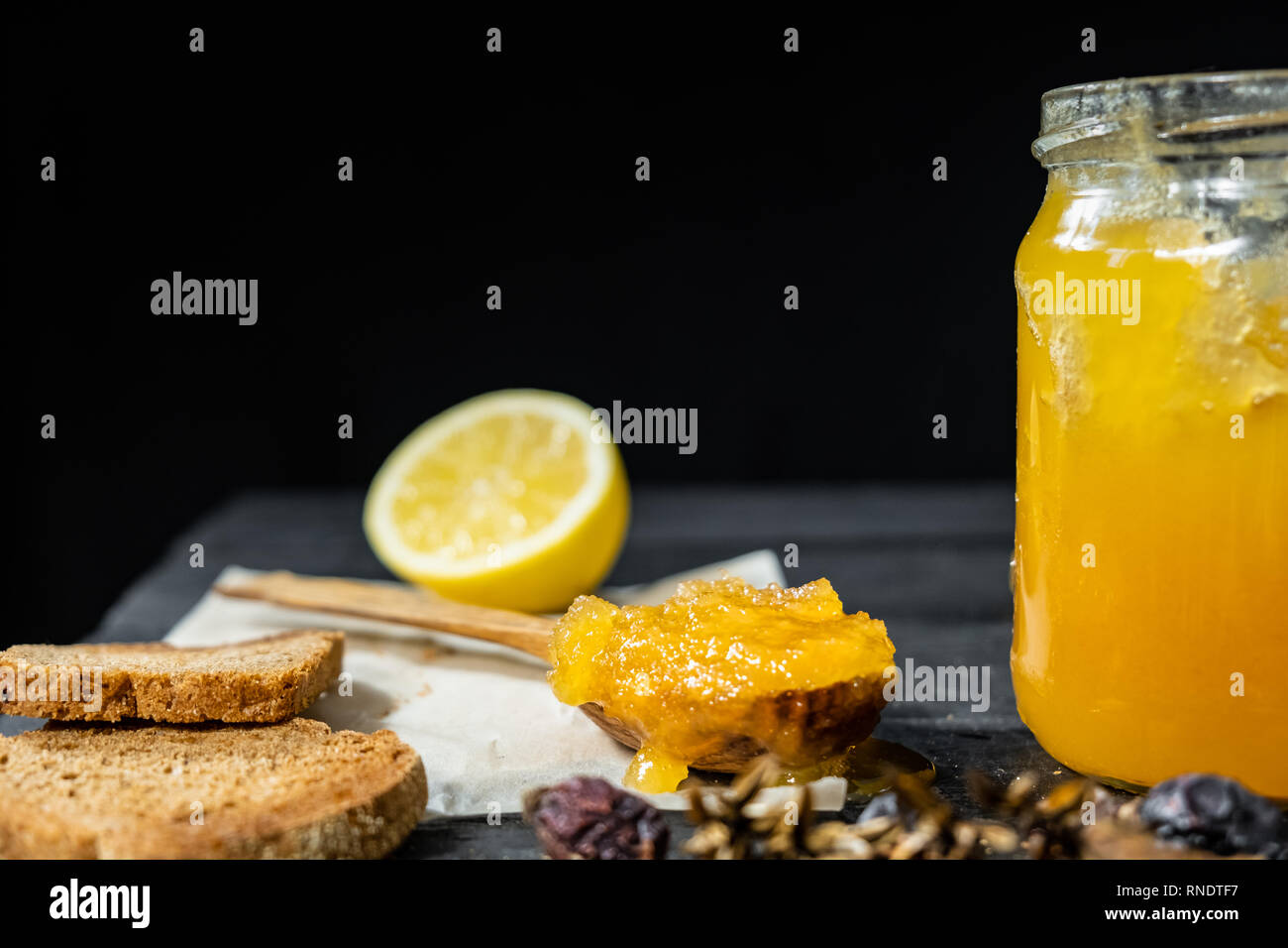 Spoonful of honey on dark rustic background. Crystallized home-made honey in jar, low-key shot Stock Photo